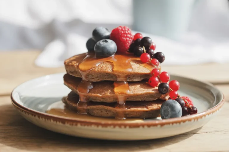 A stack of healthy gluten-free buckwheat pancakes topped with fresh berries, showcasing a nutritious breakfast choice.