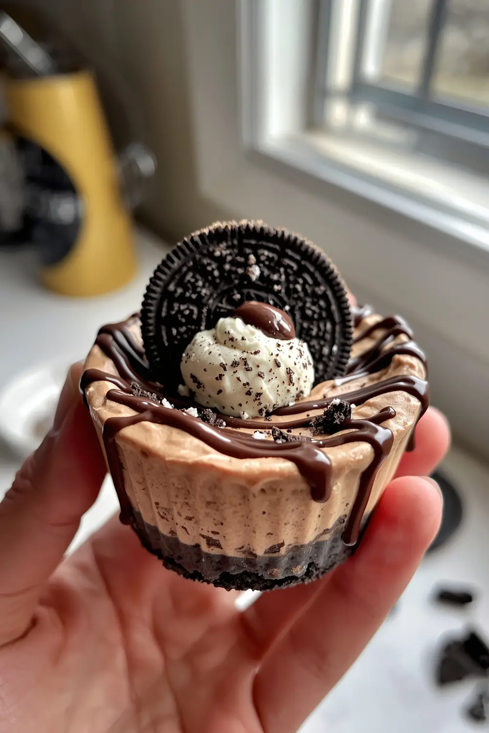 A close-up photo of a no-bake Oreo cheesecake cup with an Oreo cookie on top