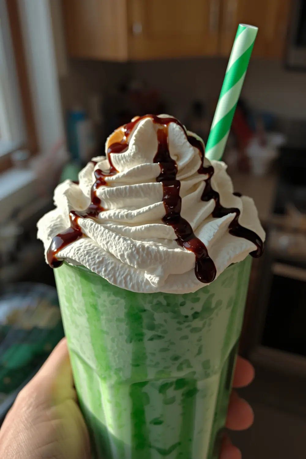A close-up of a green Shamrock Shake in a glass with whipped cream and chocolate syrup