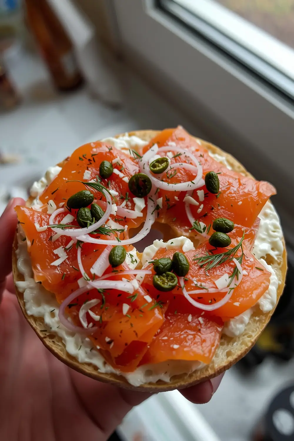 A photo of a toasted bagel with smoked salmon, cream cheese, capers, and red onion