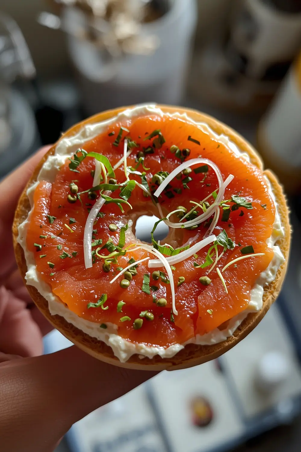 A toasted bagel topped with smoked salmon, cream cheese, dill, red onion, alfalfa sprouts, and capers