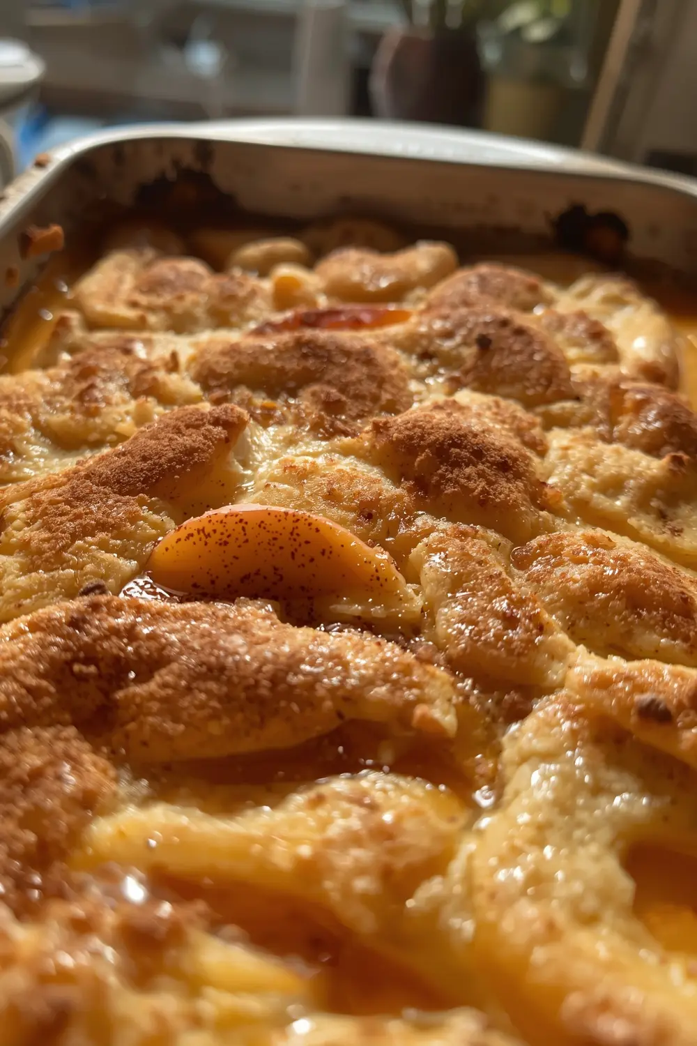 A close-up photo of a peach cobbler with a golden crust and sliced peaches